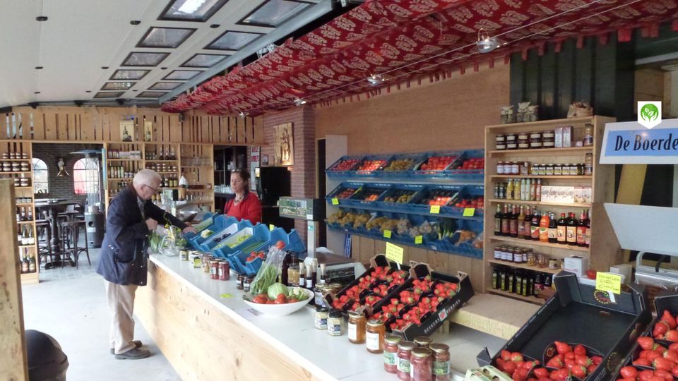 Landwinkel Kersenboomgaard en Boerderijwinkel De Ooievaar, Harmelen, provincie Utrecht, Groene Hart, interieur met vers fruit, groente, aardbeien, jam en streekproducten terwijl een klant afrekent bij de toonbank.