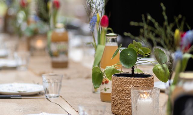 Restaurant De Boerinn, Kamerik, Groene Hart, sfeervol gedekte paastafel met bloemen, kaarsen en glazen flessen sap tijdens een brunch of groepsactiviteit in landelijke setting.