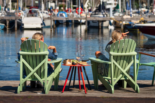Twee vrouwen zitten in loungestoelen aan het water met een drankje