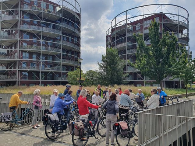 Fietsers aan tocht houden stil bij wooncomplex Hilversum Oost, Villa Industria Gashouders
