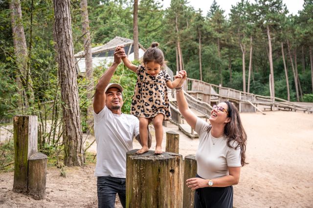 Ouders en meisje bij buitenspeeltuin