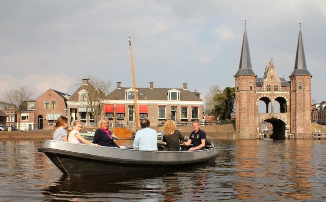Zes mensen varen in een elektrische sloep van Binnenstad Bootverhuur vlakbij de waterpoort in Sneek.