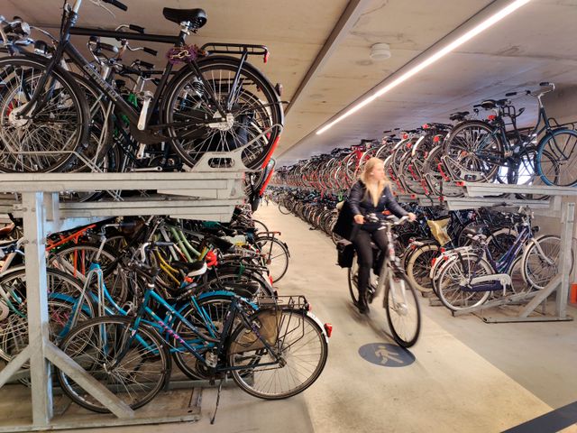 Meisje op de fiets in de fietsenstalling van het NS Station in Delft