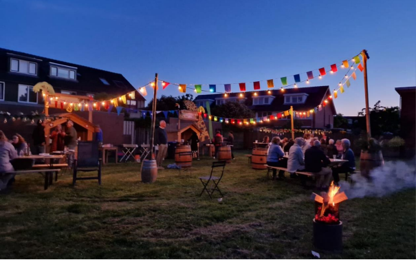 mensen in de avond bji een barbecue in een park met gekleurde vlaggetjes