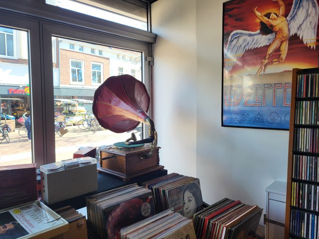 Muziekwinkel HiFi Stereo in Woerden, Groene Hart, interieur met vintage grammofoon en platenspeler tussen bakken met vinylplaten en cd’s