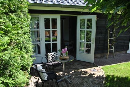 B&B Bella Rose voorkant van het huisje, met opengeslagen deuren en tuinset