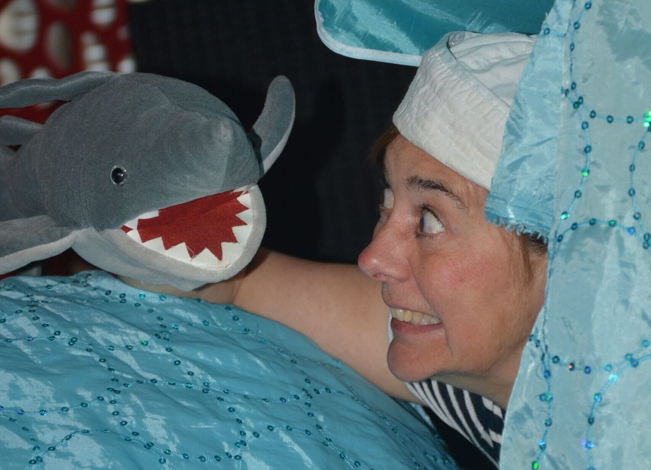 Foto van een jonge vrouw verkleedt als matroos en een handpop in de vorm van een haai.