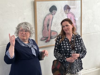 Kunstgalerie Galerie Van Slagmaat in Woerden, Groene Hart, twee vrouwen tijdens een expositie met een figuratief kunstwerk aan de wand.