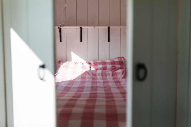 Sfeervol tweepersoonsbed met rood-wit geruite dekens in 'Huisje in de Waard' in Langerak, een knusse overnachtingsplek in het Groene Hart.