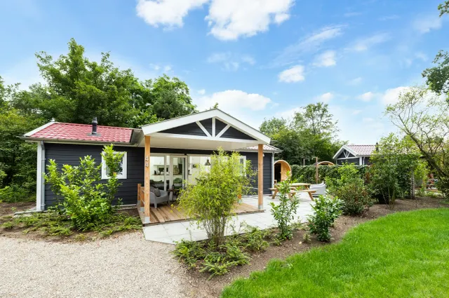 Vrijstaand vakantiehuis De Krakeling met een overdekt terras en groene tuin. Het verblijf ligt rustig tussen bomen en struiken.