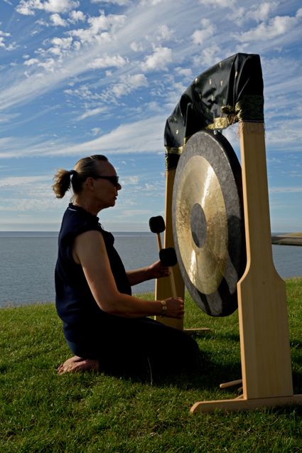 Vrouw bespeelt gong op dijk