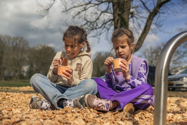 Twee kinderen eten buiten bij het Grebbelinie Bezoekerscentrum bij Fort aan de Buursteeg in Renswoude. De foto laat een ontspannen pauzemoment zien tijdens een gezinsbezoek aan de Grebbelinie.
