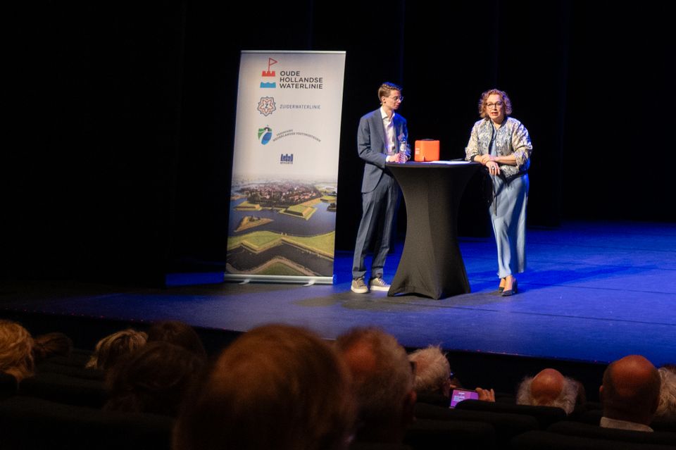 Twee mensen in gesprek op podium voor publiek