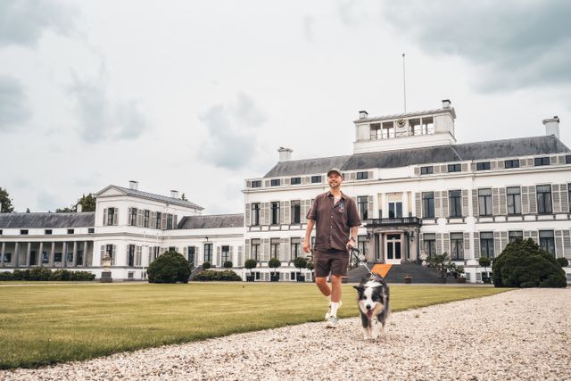 Man en zijn hond wandelen in de tuinen van Paleis Soestdijk