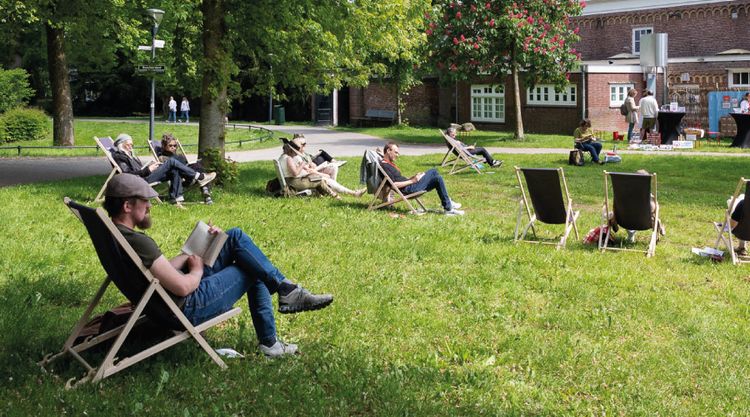 Mensen op stoelen buiten aan het lezen