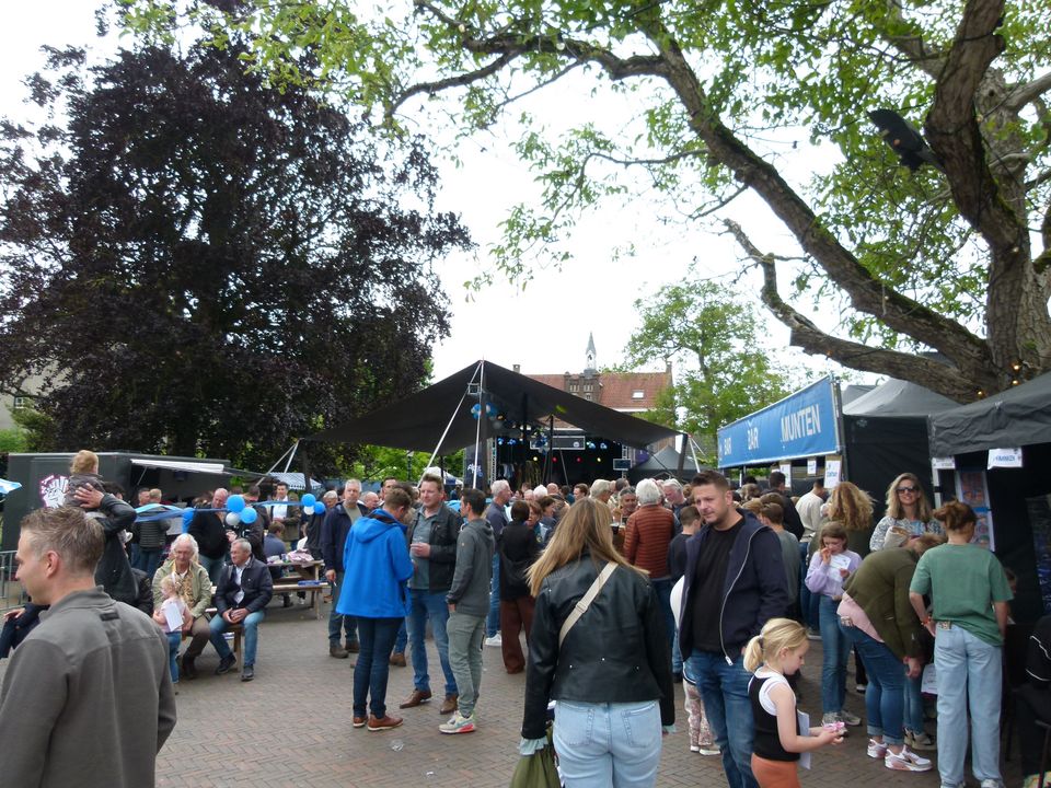 Drukbezocht festival met een publiek van volwassenen en kinderen op een plein.