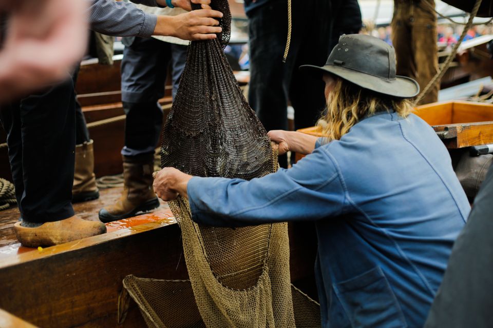 twee mensen zijn bezig met visnetten vol paling