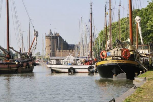 Op de voorgrond een aantal historische schepen, op de achtergrond het kasteel Muiderslot.