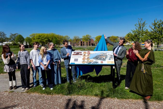 Gedeputeerde en wethouder met kinderen rondom het startpaneel van de soundgame, buiten bij het badhuis