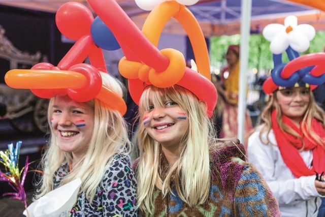 Twee meisjes met ballonnen hoedjes op Koningsdag in Delft
