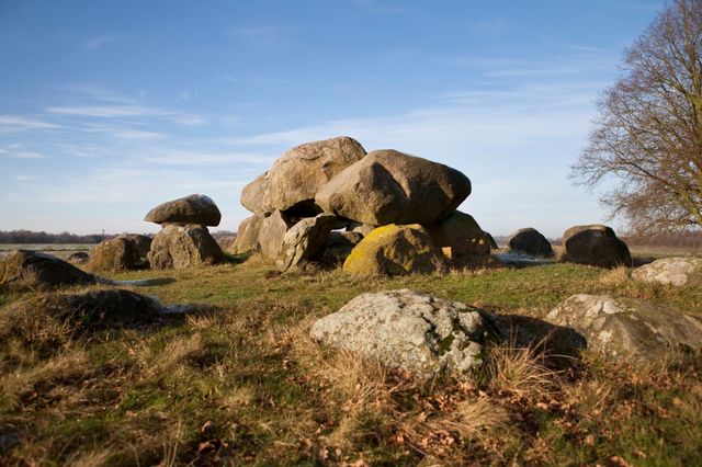 Ein Hünengrab unter einem klaren blauen Himmel, realistischer Stil, natürliche Farben, ruhige Atmosphäre