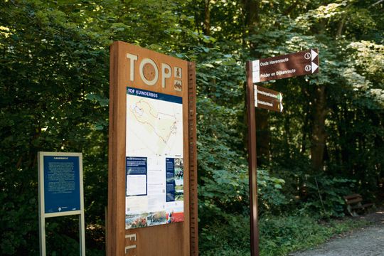 Een metalen zuil in het bos waar verschillende fiets en wandelroutes op staan aangegeven in het Kuinderbos in de Noordoostpolder.