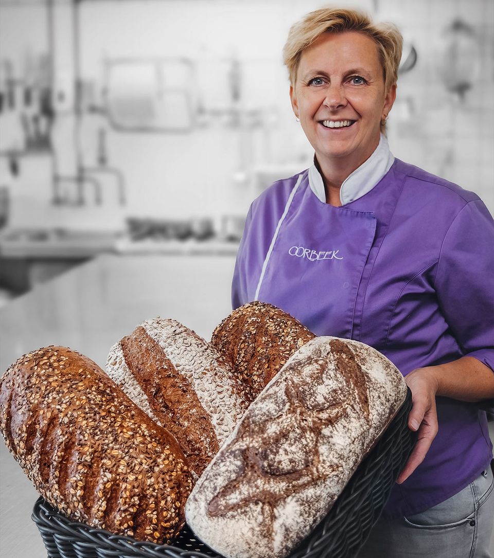 Bakker staat glimlachend met een grote mand met broden erin.