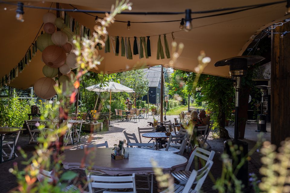 Sfeervol terras van De Eemlandhoeve met tafels en stoelen tussen het groen in het Groene Hart.