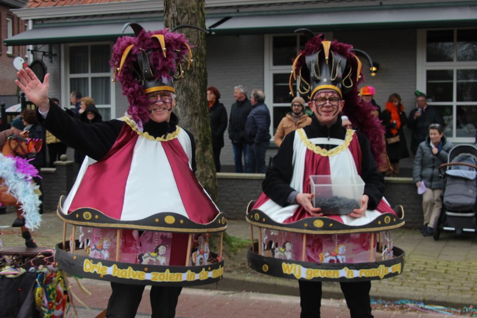 Twee mannen verkleed als draaimolen met als spreuken 'Drie halve zolen in de molen' en 'We geven een rondje weg'