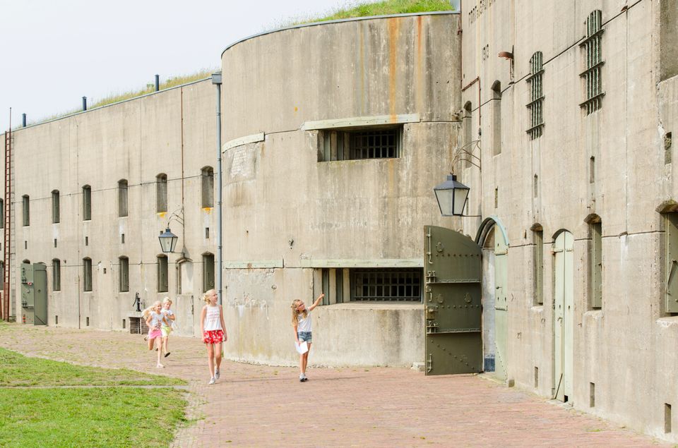Vier meisjes lopen buiten bij een groot betonnen fort