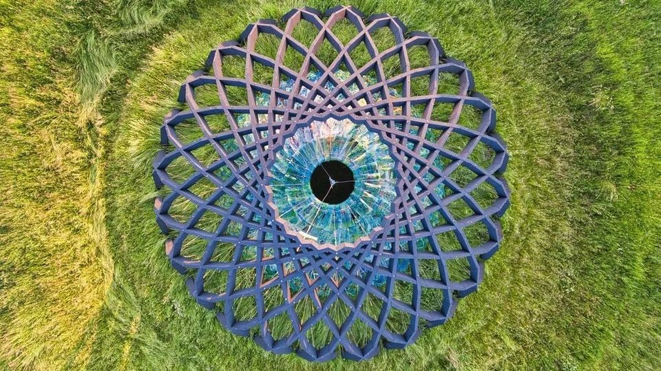Een luchtfoto van een kunstzinnig bouwwerk in een groen veld.