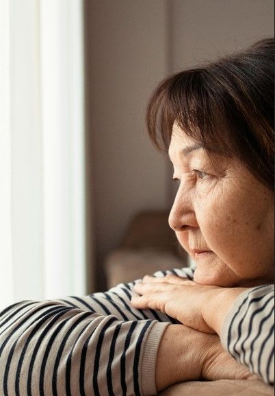 oude mevrouw die uit het raam kijkt