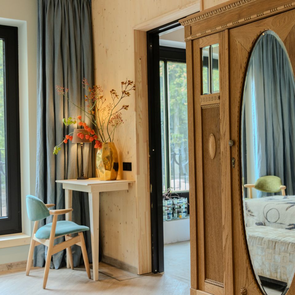 Detailfoto van een antieke kast met ovalen spiegel in een hotelkamer.