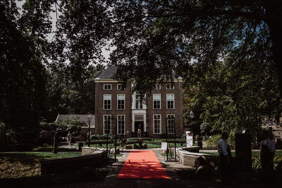 Een chateau met toegangspoort waar een rode loper voor ligt.