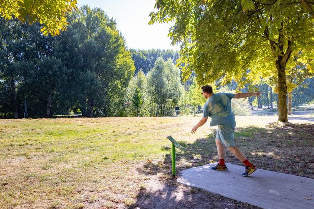 Een frisbeeer heeft net zijn frisbee weggegooid van een startpunt op het fisbee parcours.