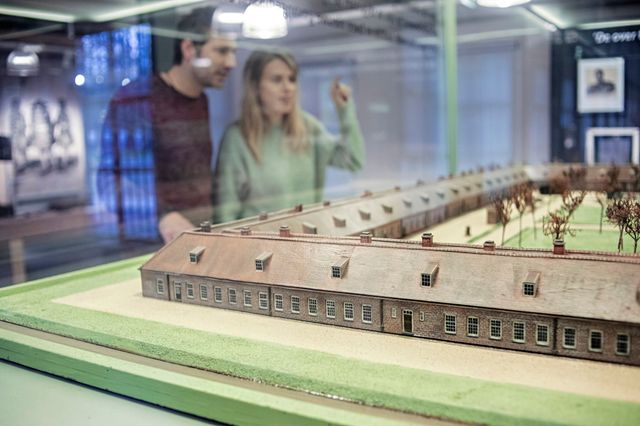 Een man en vrouw kijken naar een maquette in het gevangenismuseum.