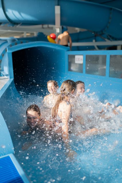 Zwembad Batenstein van WoerdenSport in Woerden, provincie Utrecht, Groene Hart, kinderen spetteren in het water bij de uitgang van een blauwe waterglijbaan.