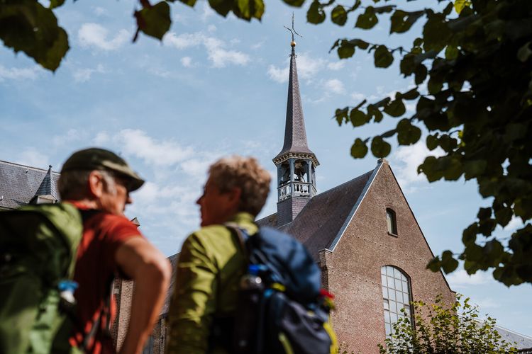 Twee wandelaars kijken naar klooster in Megen.