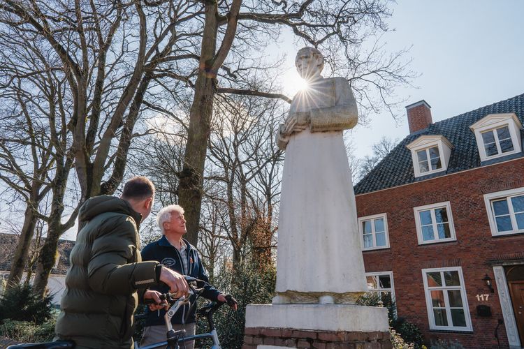 Fietsers staan bij beeld Pastoor Bastiaanse