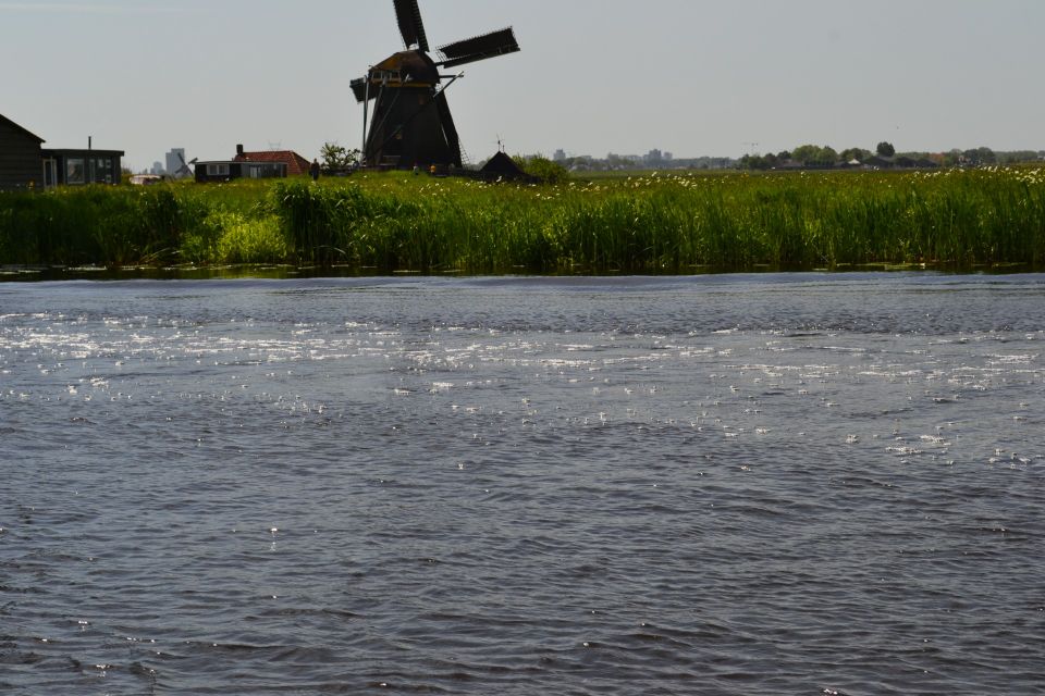 Donkere Waterloosmolen vanuit het water te zien op afstand in Rijpwetering