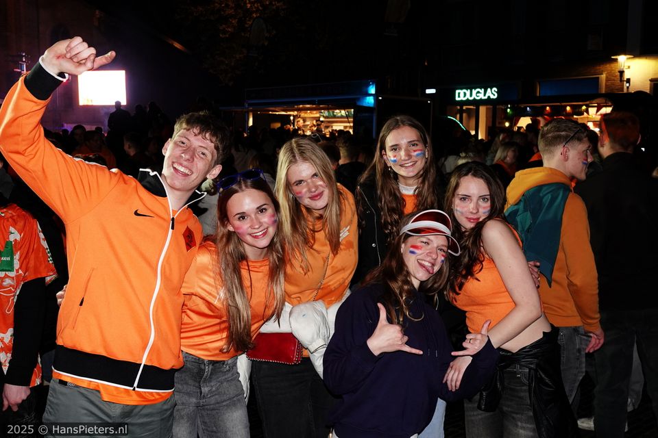 Uitgaansevenement Koningsnacht in Woerden, Groene Hart, groep feestende jongeren in oranje kleding met rood-wit-blauwe schmink op het Kerkplein tijdens het avondfeest in de binnenstad.