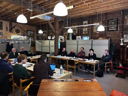 Groep mensen zit aan tafels in vergaderopstelling