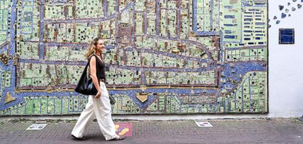Meisje loopt langs de keramieken kaart van Delft