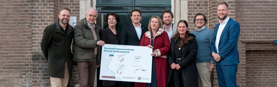 Groep mensen staat voor gebouw met handtekeningenbord in de hand