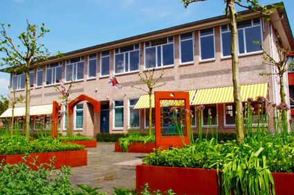 Het Bridgemuseum in Leerdam van buiten, voor de deur een groen tuintje.