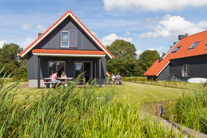 Vakantiehuis van RCN de Potten in Offingawier van de buitenkant met verschillende mensen die op het terras genieten van de zon.