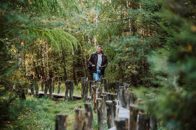 Ein Mann geht auf einem Bretterweg in der Natur.
