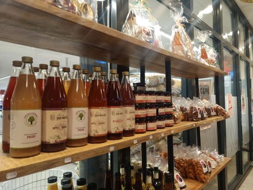 Schappen met flessen sap, potjes jam, zakken noten en cadeau pakketten.