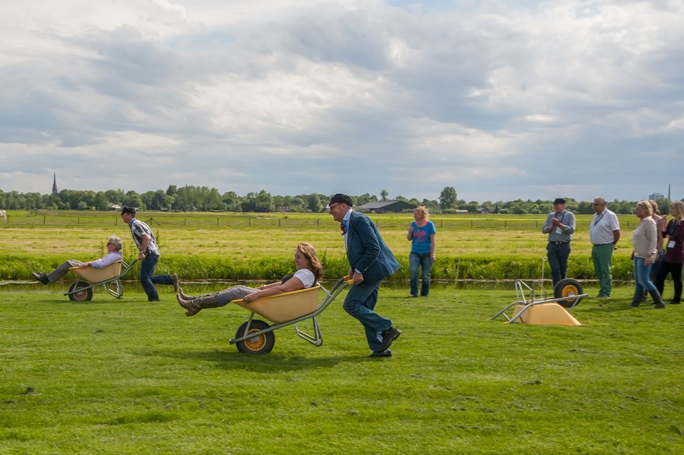 Boerderij De Boerinn in Kamerik, Groene Hart, boerenspellen met kruiwagenrace als groepsactiviteit en teamuitje in het weiland met deelnemers en toeschouwers.