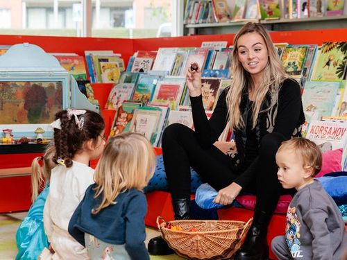 Een vrouw met kinderen in de bibliotheek